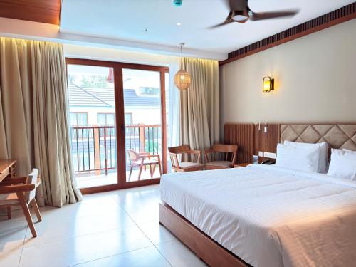 a bedroom with a large bed and a balcony at KTDC Malabar Courtyard in Mulappilangād