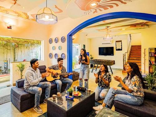 a group of people sitting in a living room playing guitar at The Hosteller Goa, Anjuna in Arpora