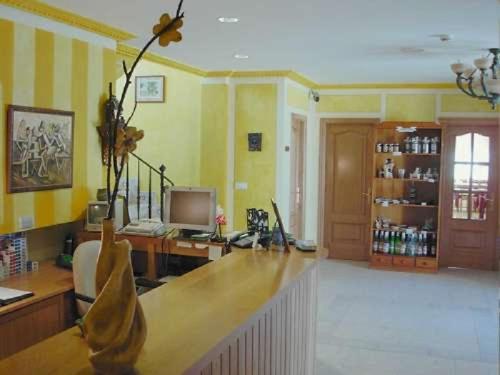 a living room with yellow walls and a desk with a computer at Posada La Anjana in Puente Viesgo