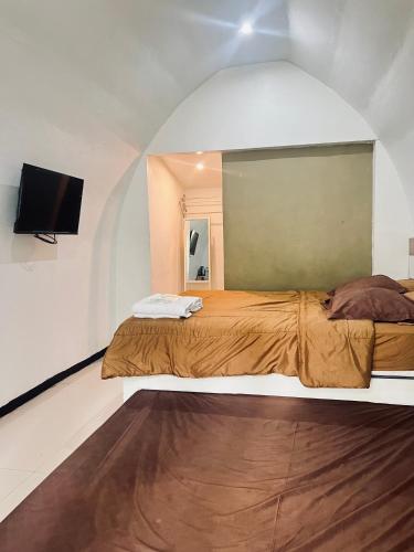 a bedroom with a bed and a flat screen tv at Pagupon Camp Syariah in Batu