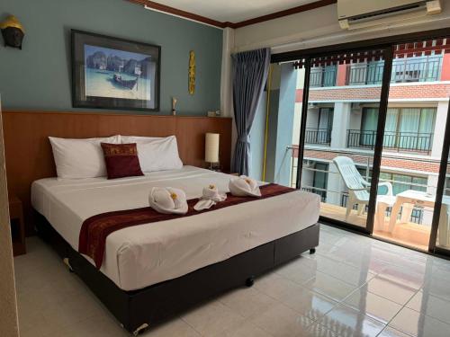 a bedroom with a large bed with a large window at Flowernight Guesthouse in Kata Beach