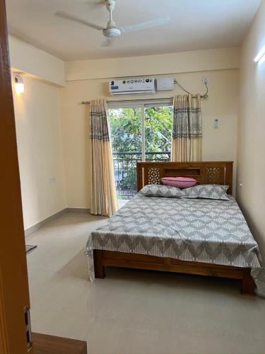 a bedroom with a bed and a large window at Krisna vykundam in Guruvāyūr