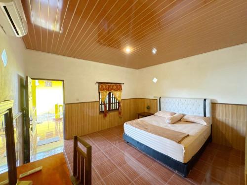 a bedroom with a bed and a wooden ceiling at Harus Damai Inn in Lagudri