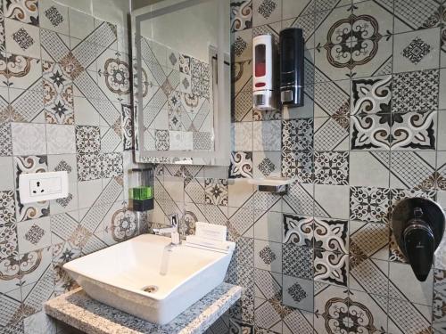 a bathroom with a sink and a mirror and tiles at Motel Oracle in Debra