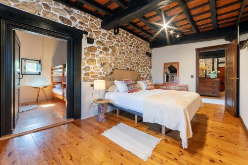 a bedroom with a bed and a stone wall at La Quintana de Los Valles in Benia de Onís