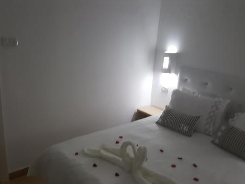 a bedroom with a white bed with flowers on it at Zimmer Belev HaKikar- Dead sea in Neʼot HaKikar