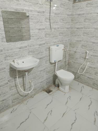 a white bathroom with a toilet and a sink at Cnc in Vadodara