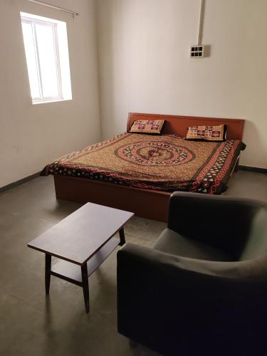 a bedroom with a bed and a table and a chair at Cnc in Vadodara
