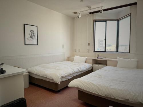 ein Zimmer mit zwei Betten und einem Fenster in der Unterkunft Hotel Sun Road in Amakusa