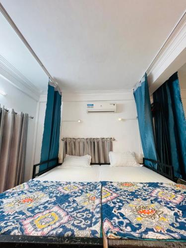 a bed in a small room with blue curtains at Friendly House Hostel Huế in Hue