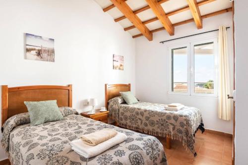 a bedroom with two beds and a window at Villa Santi I by Villa Plus in Cala en Porter