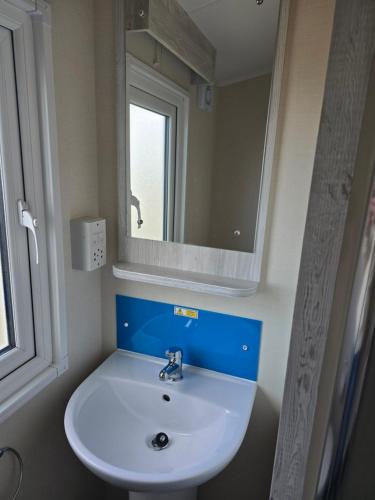 a bathroom with a white sink and a mirror at Palm trees and the sea in Reighton