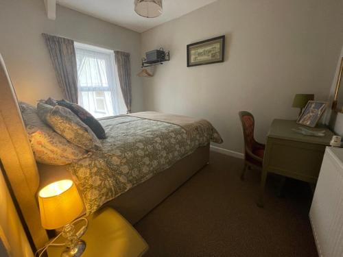 a bedroom with a bed and a table and a window at 3 Stable Mews in Holsworthy
