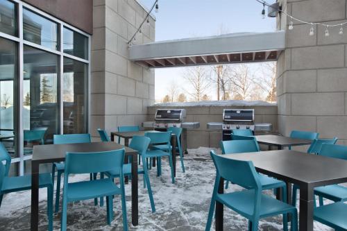 a restaurant with tables and blue chairs at Home2 Suites by Hilton Anchorage/Midtown in Anchorage