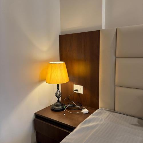 a lamp sitting on a dresser next to a bed at Stayverse noida in Greater Noida