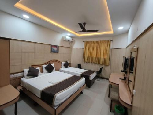 a hotel room with two beds and a television at Anand Regency Majestic in Bangalore