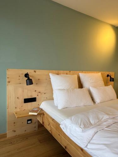 a bedroom with a wooden bed with white pillows at "Unter Freunden", Design Meets Allgäu in Wertach