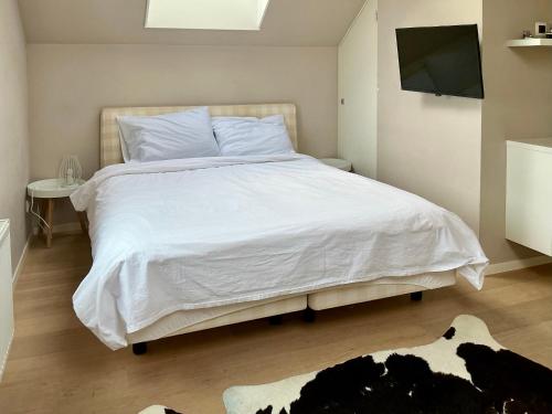 a bedroom with a large white bed with a television at Oomes Huus - Sleep by Hästens, Wake with Coffee in Den Hoorn