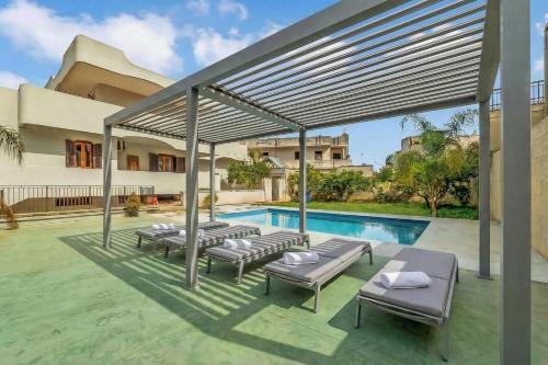 a group of lounge chairs and a swimming pool at Tenuta VillaMar Rooms in Cursi