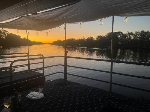 a boat on a river with the sunset in the background at Mandurah Houseboat Just Chillin in Mandurah