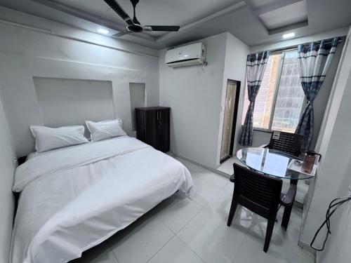 a bedroom with a bed and a glass table at Radha Krishna Guest House in Surat