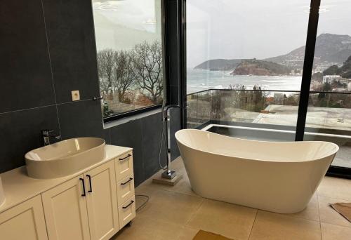 a bathroom with a tub and a sink and a window at Villa Mr Richard in Sutomore
