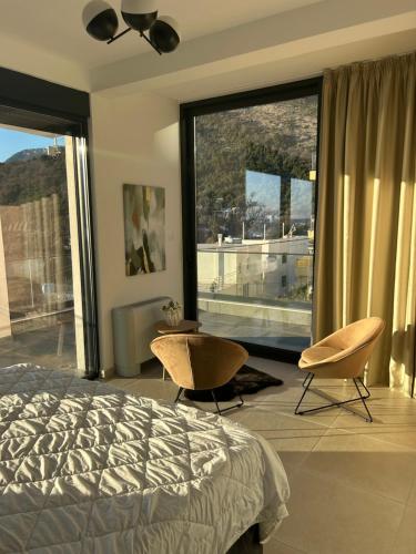 a bedroom with a bed and two chairs and a large window at Villa Mr Richard in Sutomore
