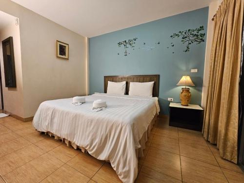 a bedroom with a large bed with a white blanket at Baan Suksiri Hotel Hua Hin in Hua Hin