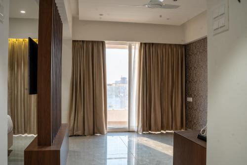 a living room with a large window with curtains at Millennium Hotel in Nashik