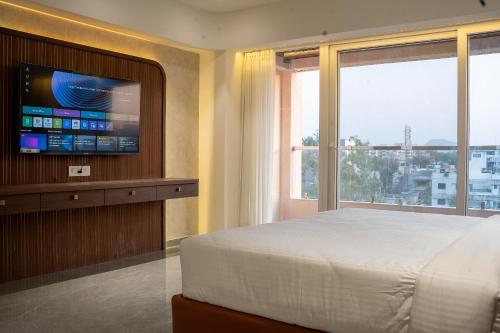 a bedroom with a bed and a tv and a window at Millennium Hotel in Nashik