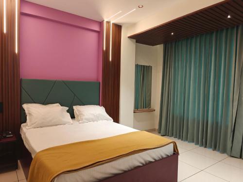 a bedroom with a large bed with a purple wall at Hotel Jagdamb Kolhapur in Kolhapur