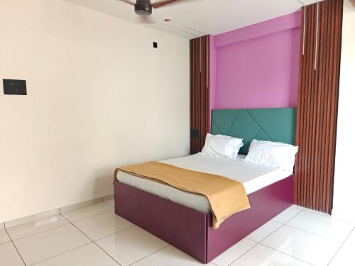 a bed with a colorful headboard in a room at Hotel Jagdamb Kolhapur in Kolhapur