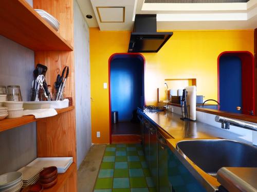 a kitchen with yellow and blue walls and a sink at Garden BBQ and Stay ANCHOR in Miyakojima