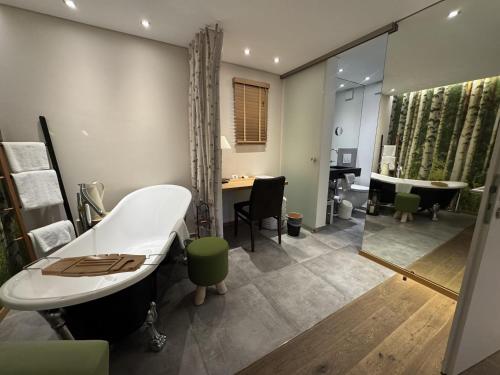 a bathroom with a tub and a sink and a desk at Hotel Schindlerhof in Nuremberg
