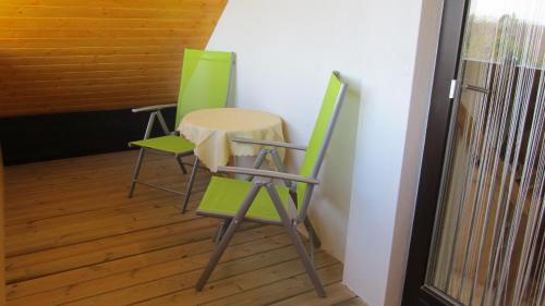 two green chairs and a table in a room at Pension Maria Wallner in Bad Gams