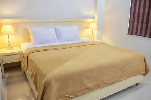 a bed in a hotel room with two lamps at Miracle Hotel Manado in Manado