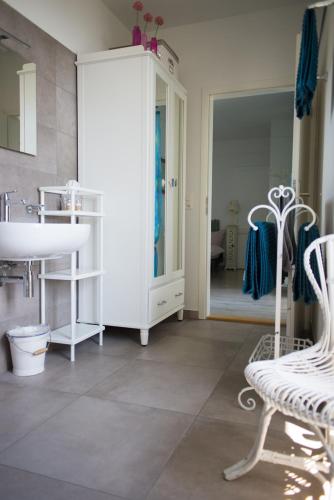 a bathroom with a sink and a white cabinet at Hôtel de la Béroche in Saint Aubin Sauges