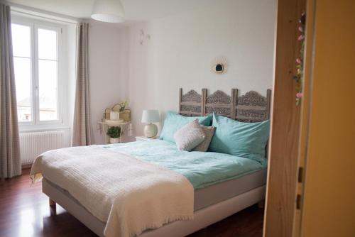 a bedroom with a bed with blue sheets and a window at Hôtel de la Béroche in Saint Aubin Sauges