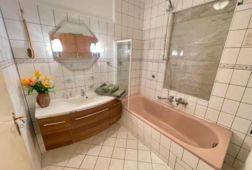 a bathroom with a pink tub and a sink at Strand Haus Am Walde in Trassenheide