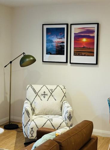 a living room with a chair and pictures on the wall at Clare Escape Ballycastle - Luxury town centre apartment, walk to beach & harbour, near Giants Causeway in Ballycastle
