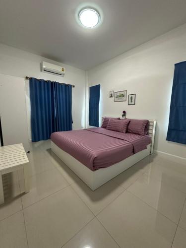 a bedroom with a bed with purple sheets and blue curtains at Baanpeanutsvilla Huahin in Hua Hin
