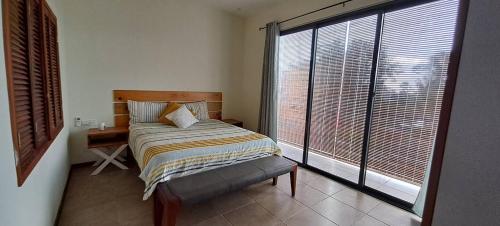 a bedroom with a bed and a large window at Les Villas Thorel - Hibiscus in Rivière Noire