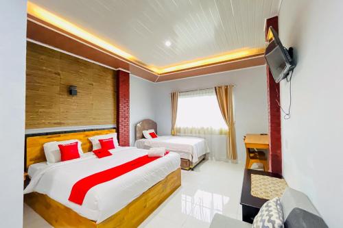 a hotel room with two beds and a television at RedDoorz at Hotel Dieng Berastagi in Berastagi