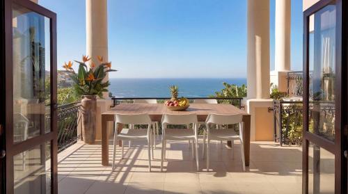 a table and chairs on a balcony with the ocean at Villa Seaview, Private Oceanfront Villa, Heated Pool & Whale Watching Views, Knysna Heads in Knysna