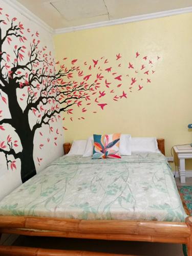 a bedroom with a tree with birds on the wall at Cronin Residences in Oslob
