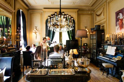 a bar with people sitting in a room with a chandelier at Charmehotel Manoir Ogygia in Poperinge