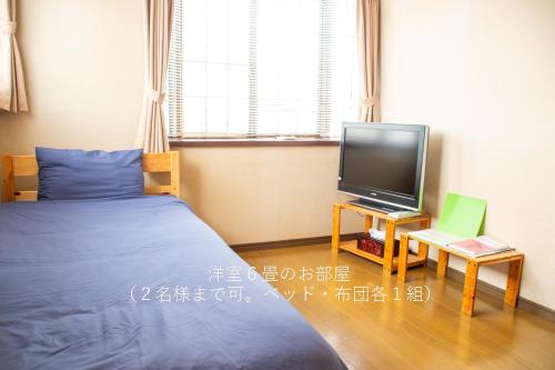 a bedroom with a bed and a tv on a table at 民泊よこてこよ in Yokote