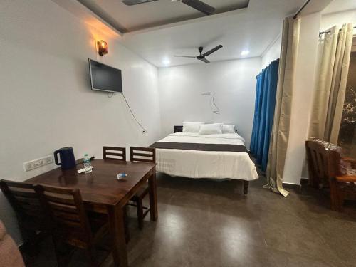 a bedroom with a bed and a table and a tv at Waves - for Family & Married Couples only in Mahabalipuram