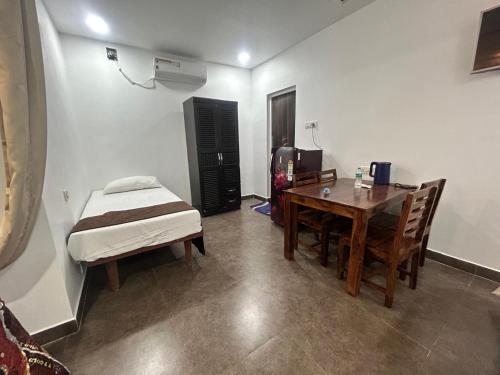 a room with a table and a bed and a table and chairs at Waves - for Family & Married Couples only in Mahabalipuram
