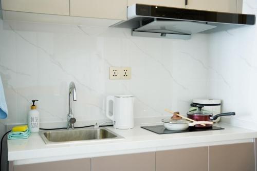 a white kitchen with a sink and a counter top at Urban Sanctuary Riva Phnom Penh in Phnom Penh